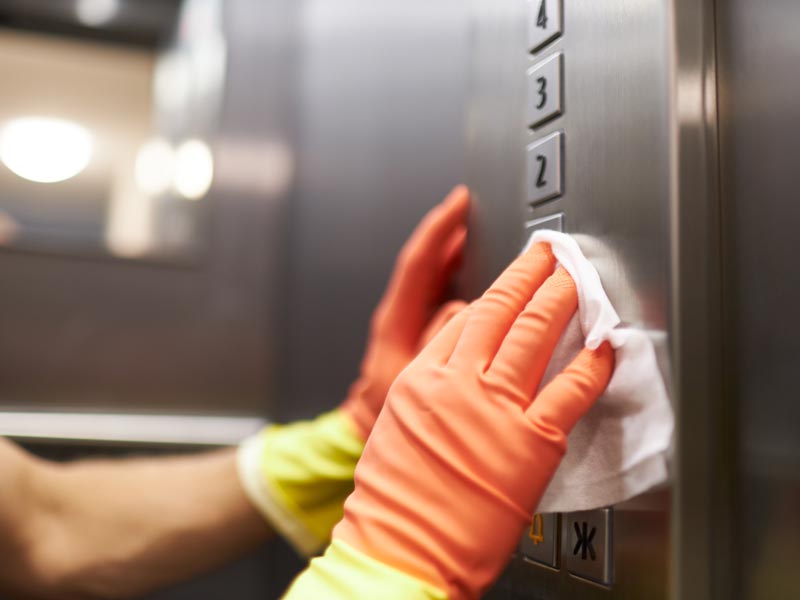 professional cleaner sanitizing elevator buttons