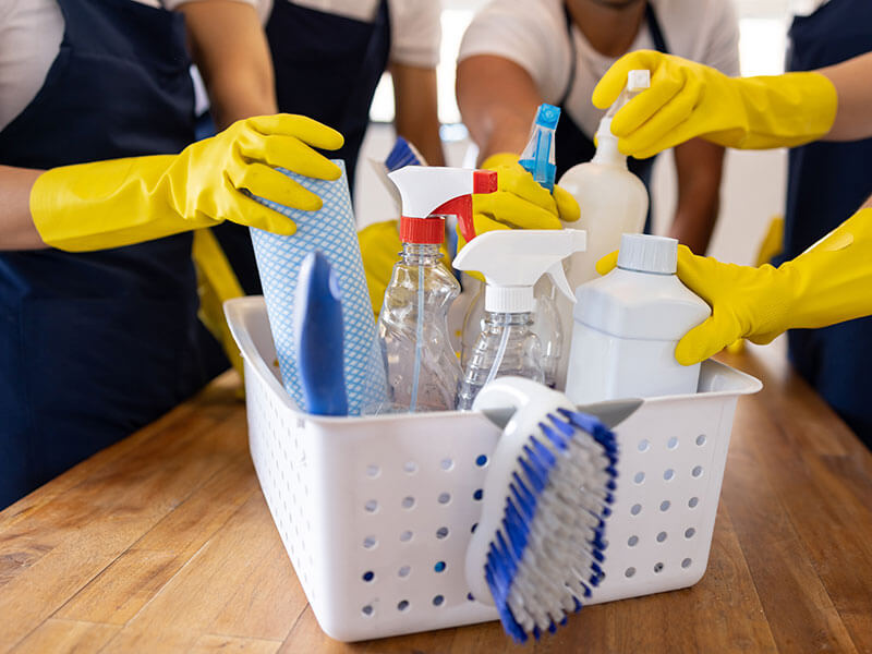 basket of cleaning supplies being grabbed at by workers